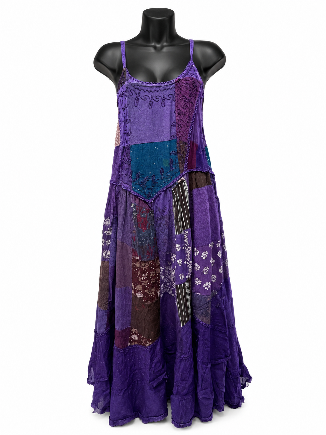 A purple patchwork maxi dress with floral and lace details, displayed on a black mannequin torso against a white background.