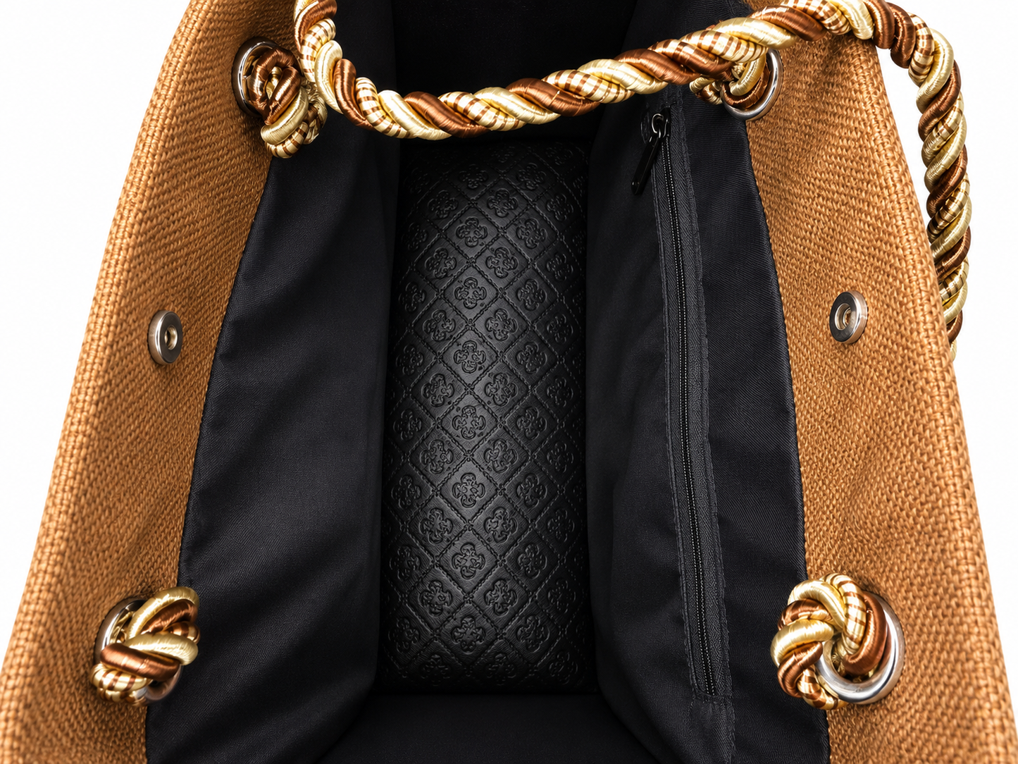 Close-up of a tote bag interior showing a black quilted patterned center panel, black zipper pocket, black fabric lining, and twisted rope handles in tan and gold with metal ring attachments.