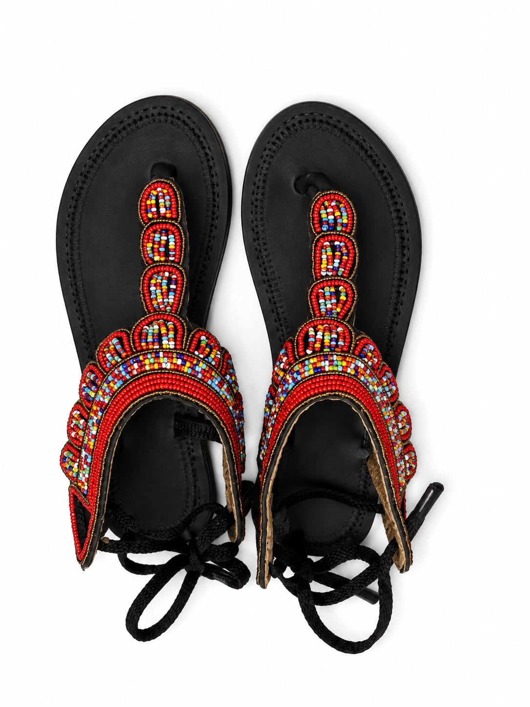 A pair of black leather sandals decorated with intricate red, orange, yellow, and blue beaded patterns on the straps, shown from a top-down view on a white background.