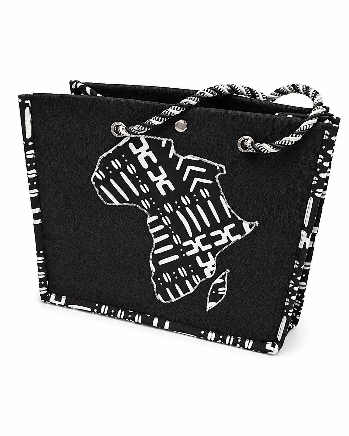 A black canvas tote bag with a white patterned border, rope handles, and a white graphic silhouette of Africa on the front, shown on a plain white background.