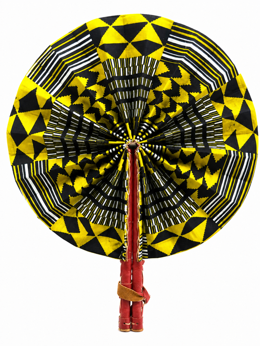 A circular hand fan with a bold geometric pattern in yellow, black, and white, featuring red wooden handles wrapped with a brown leather strap, isolated on a white background.